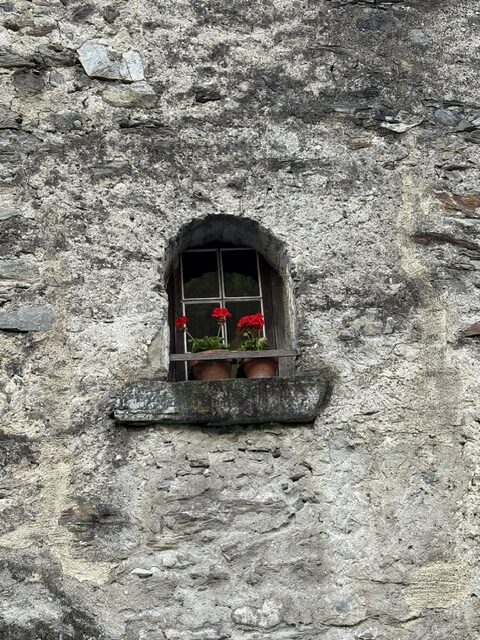 Small window in an old Swiss house symbolising community living, privacy and being witnessed